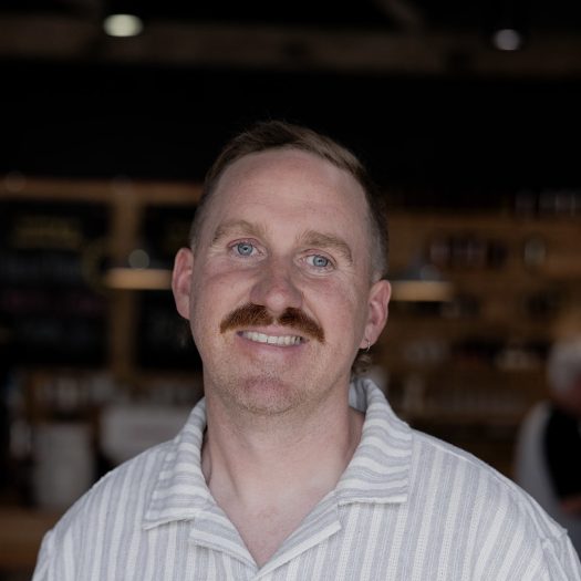 Hamlet team member, Jim, smiling with a white striped, collared shirt.